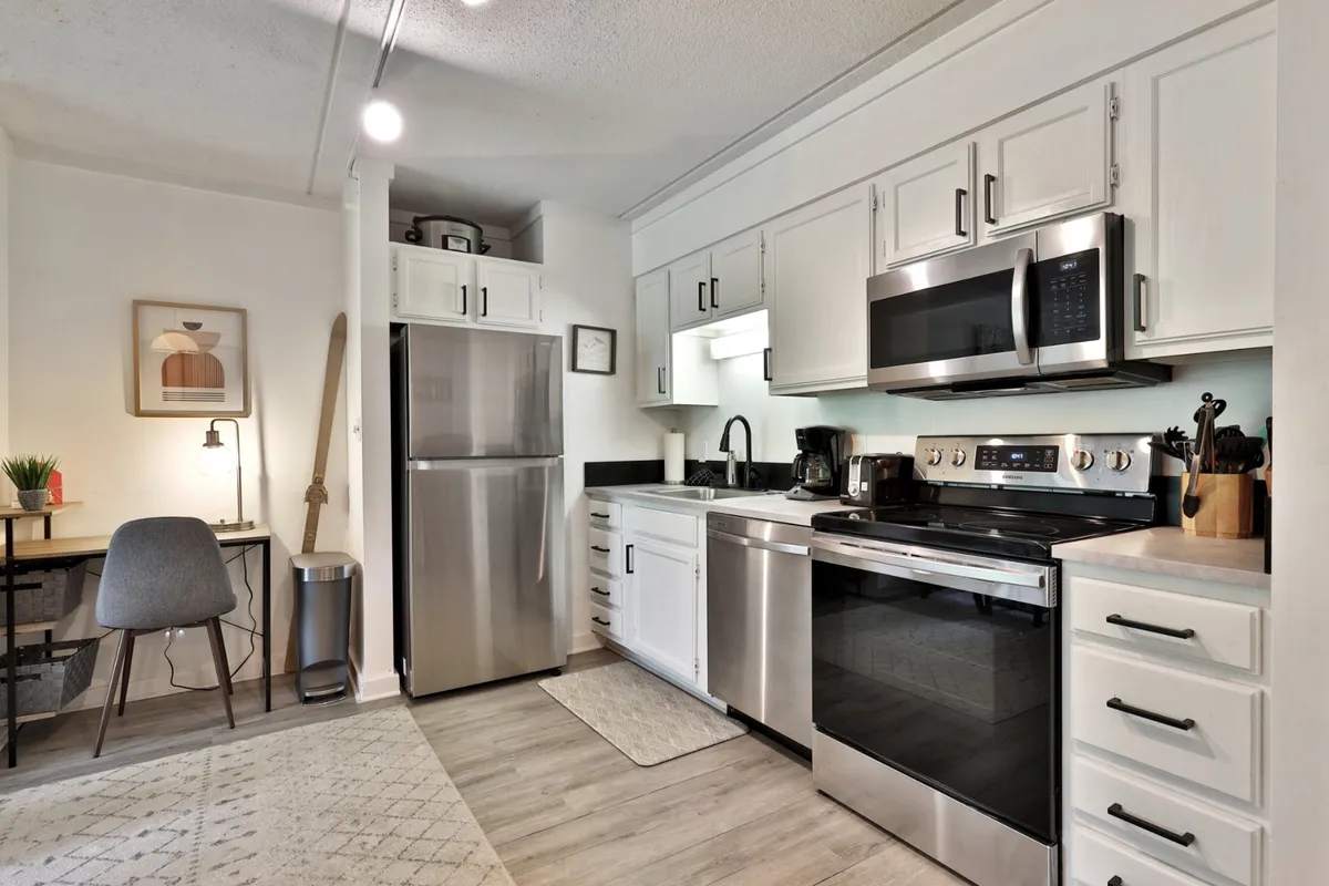A cozy kitchen scene with a kitchen island, stainless steel appliances, and a small adjacent dining area. The intimate setup encourages shared meals, coffee breaks, and friendly conversations, echoing the spirit of togetherness and functionality.