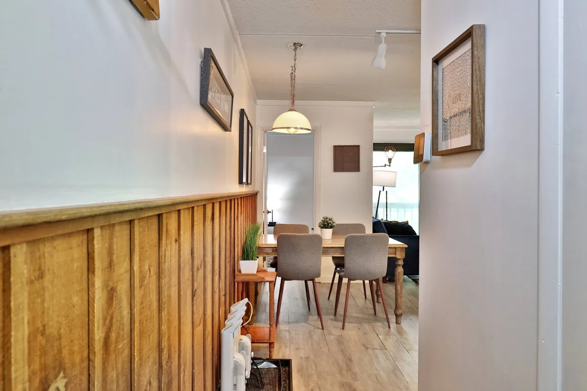 A warm dining nook with wood paneling, a central dining table ready for gatherings, and a hanging light fixture that creates a cozy, inviting atmosphere. Framed artwork adds a personal touch, making the space ideal for family dinners or planning adventures.