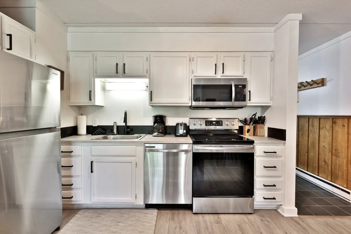 A modern kitchen featuring gleaming stainless steel appliances, a central island for food prep and gathering, and sleek cabinetry. The space is bright and open, inviting both the chef and guests to interact. Subtle decorative accents, such as a bowl of fruit or kitchenware, enhance the sense of readiness for any meal or culinary adventure.