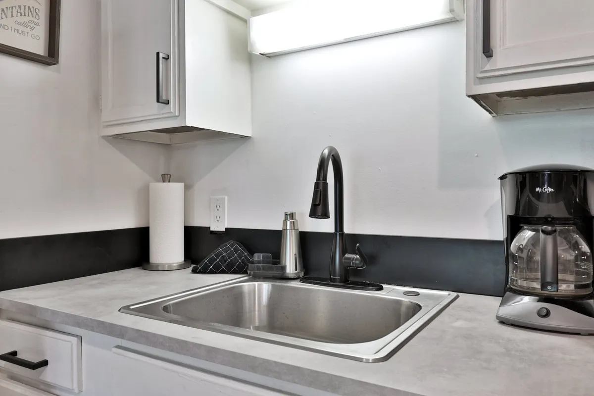 A kitchen corner featuring a sink, faucet, and coffee maker, suggesting a ready spot for morning rituals or mid-day breaks. The inviting setup hints at the comforts of home, such as brewing coffee while preparing for a productive workday.